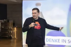 Christian Dietz mit Mikrofon zeigt auf die Leinwand