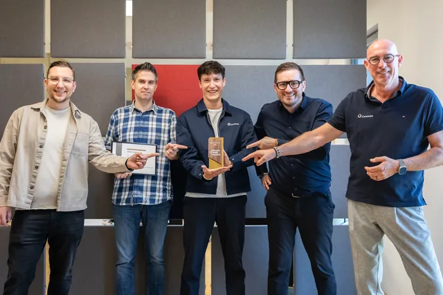 Fünf Männer in einem Büro mit Pokal und Urkunde des Neuro Web Award 2026, alle zeigen auf den Pokal in der Mitte: Alexander Sapegin, Christoph Reinartz, Lieven Griebeling, Christian Dietz und Rainer Hansen