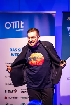 Christian Dietz öffnet lachend sein Sakko und zeigt das FRED-T-Shirt