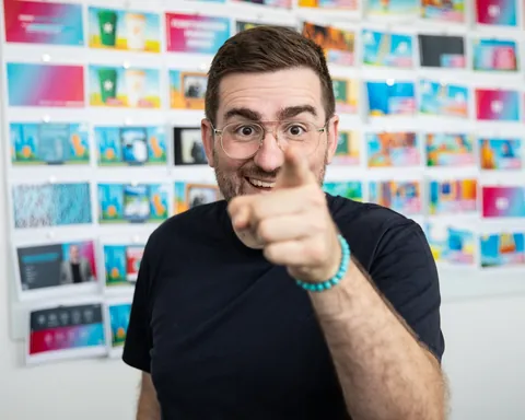 Christian Dietz laughing and pointing at the camera, a wall full of colourful slides behind him